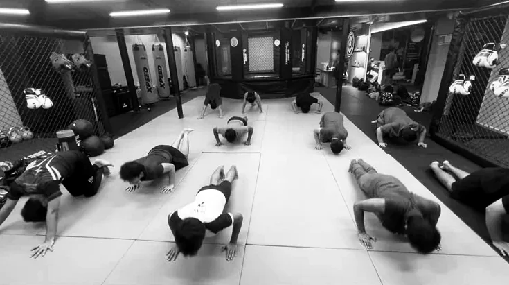 A full class doing push-ups together on the mats